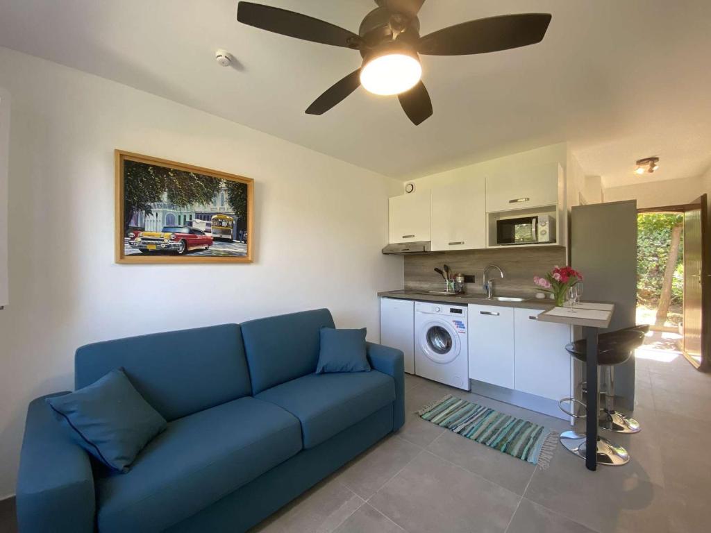 un salon avec un canapé bleu et une cuisine dans l'établissement Studio refait à neuf avec piscine et parking, Les Issambres - FR-1-226-495, à Saint-Peïre-sur-Mer