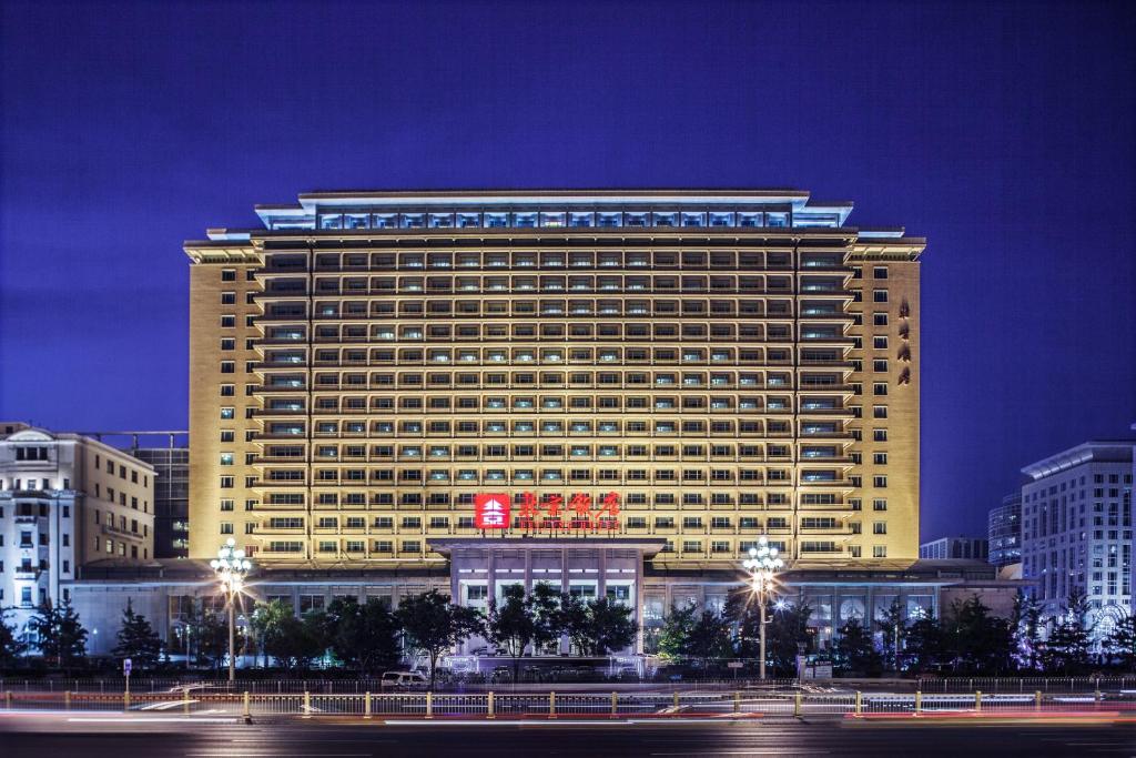 een groot geel gebouw met 's nachts een bord erop bij Beijing Hotel in Beijing