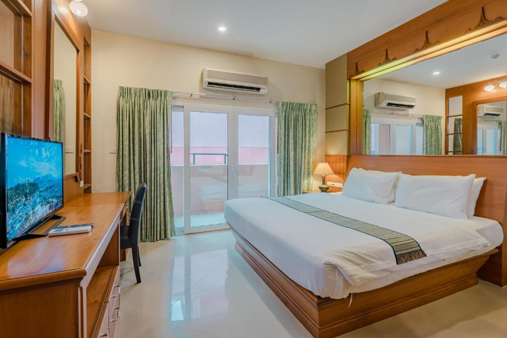 een slaapkamer met een bed, een bureau en een televisie bij Whitehouse Condotel in Pattaya