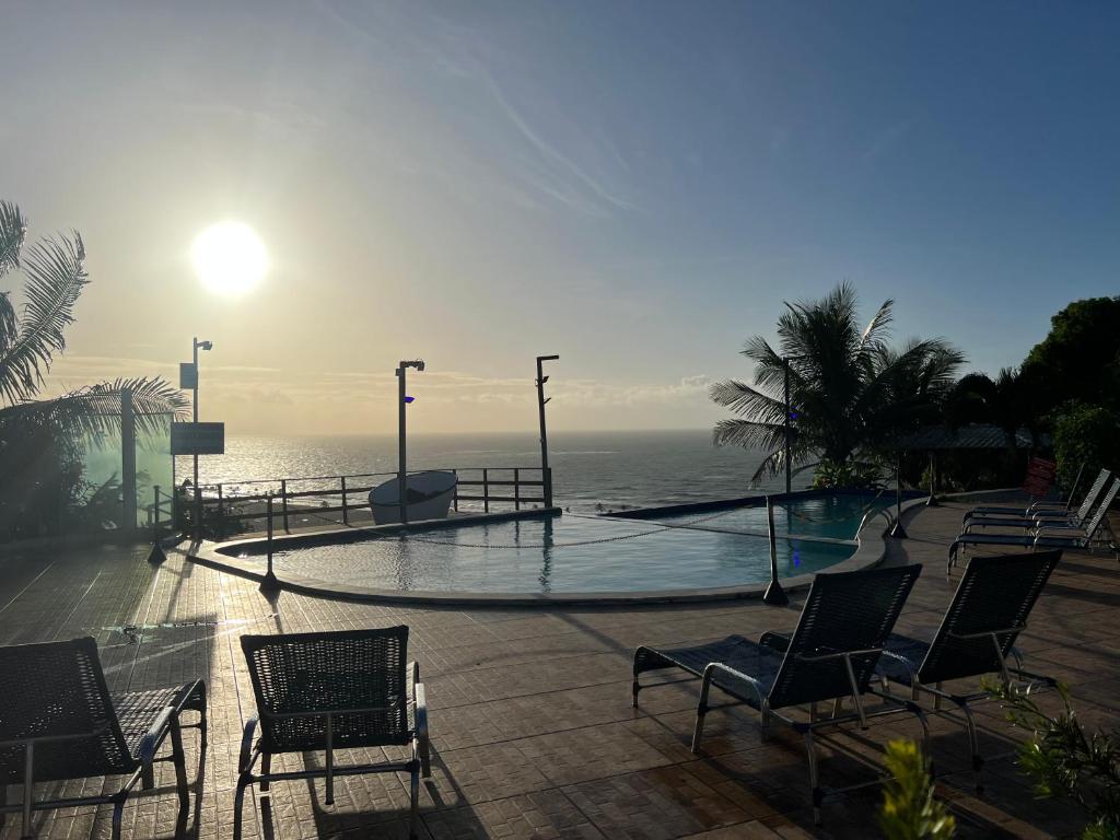 einen Pool mit Stühlen und das Meer im Hintergrund in der Unterkunft Pousada Paradise Vista do Atlantico in Maceió