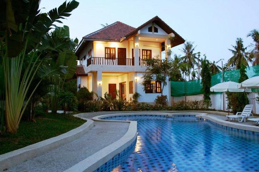 a house with a swimming pool in front of a house at Baan Jasmin Village in Choeng Mon Beach
