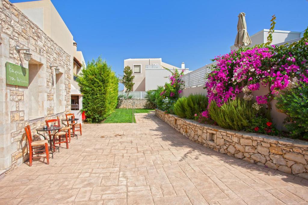 patio z krzesłami i kwiatami obok budynku w obiekcie Salvia Villas w mieście Skouloúfia