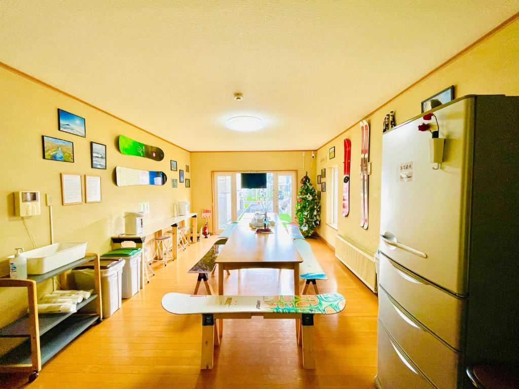 um quarto com uma mesa longa e um frigorífico em Yellow House Niseko em Kutchan
