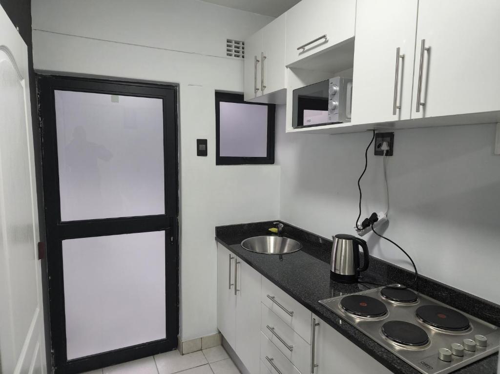 a small kitchen with a sink and a stove at Grace Villas modern studio apartments in East London