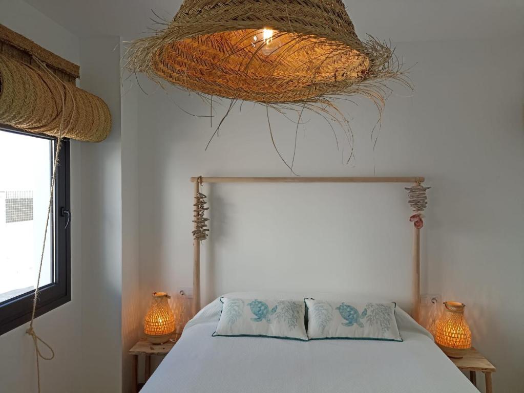a bedroom with a bed and a basket hanging from the ceiling at Mirador de Trafalgar Conil in Conil de la Frontera