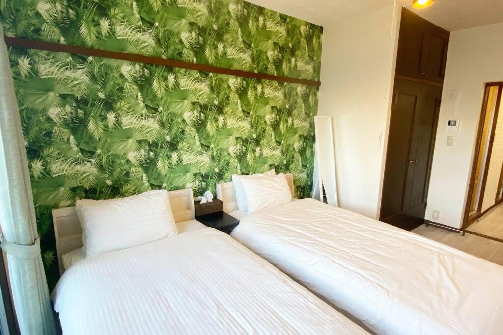 two beds in a bedroom with a green wall at ラ・ポート空港前101 in Shime
