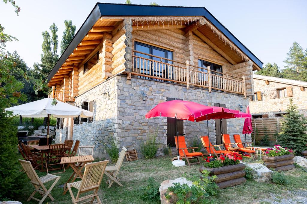 une cabane en rondins avec des tables, des chaises et des parasols dans l'établissement Les Flocons de Neige, à Bolquère-Pyrénées 2000