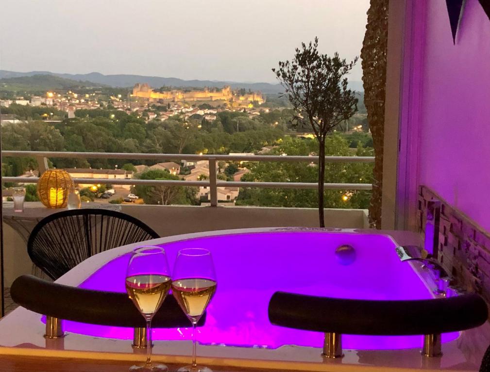 uma banheira de hidromassagem com 2 copos de vinho na varanda em Panorama Suite romantique & Spa em Carcassonne