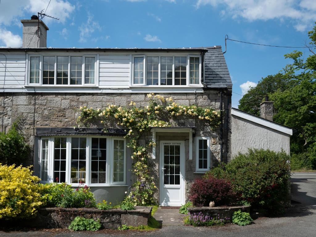 an old stone house with flowers on it at Corner Cottage in Beaumaris