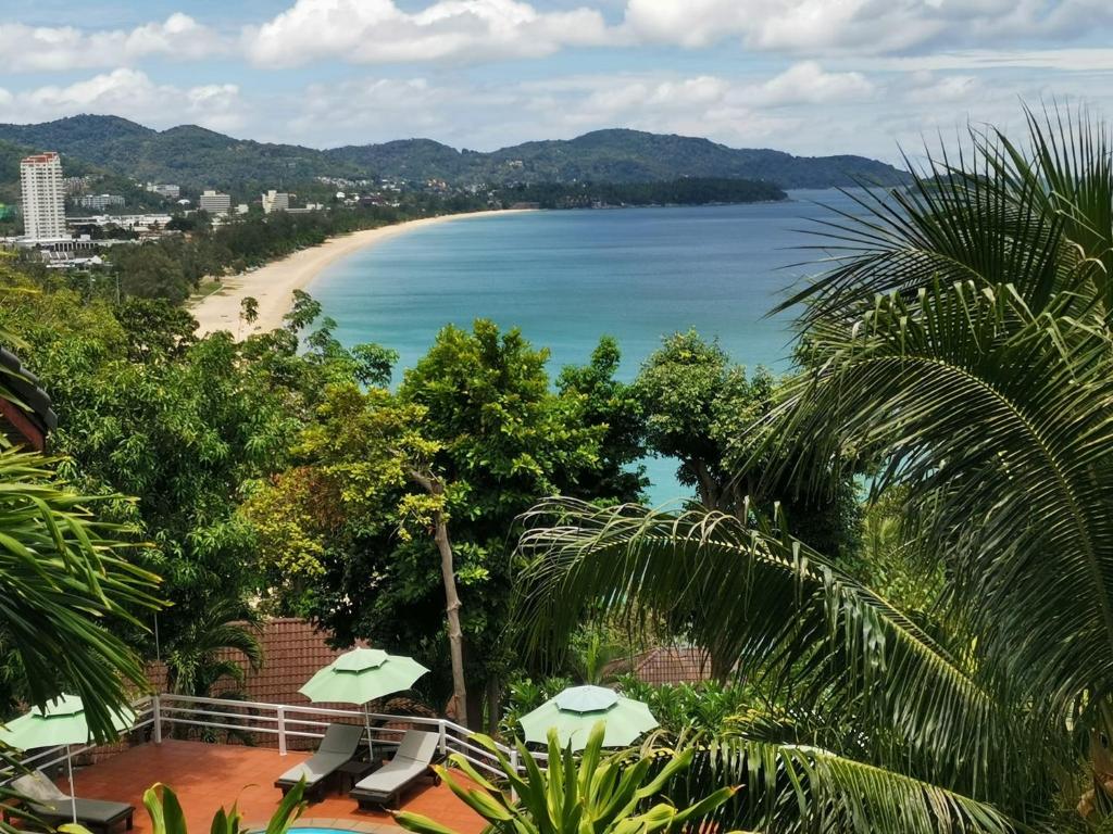 a view of a beach from a balcony with umbrellas at On The Hill Karon Resort in Karon Beach