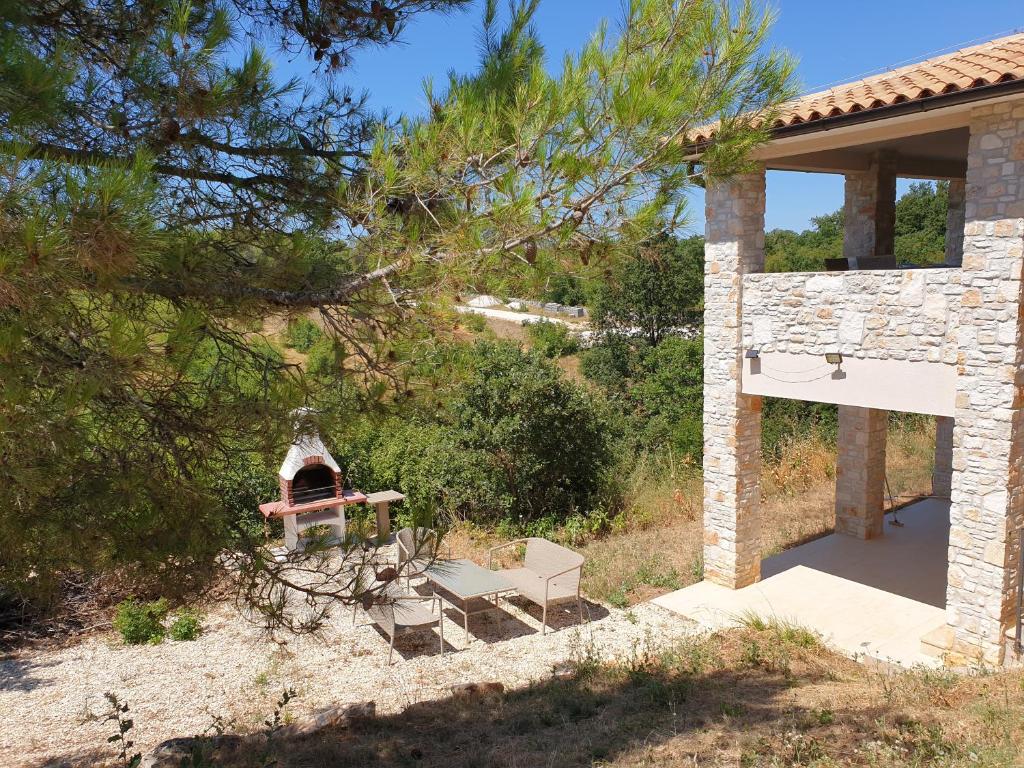 a stone house with a picnic table and a fireplace at Villa Istra in Divšići