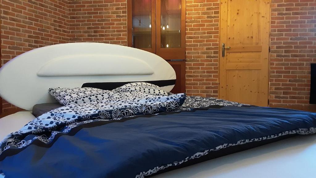una cama azul con almohadas encima en HOTEL DU BERRY - Loveroom avec Sauna, Hammam, Jacuzzi privatifs, en Reuilly