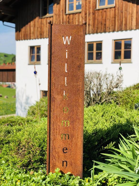 a sign in the grass in front of a house at Ferienwohnungen Britta Heim in Oberstaufen