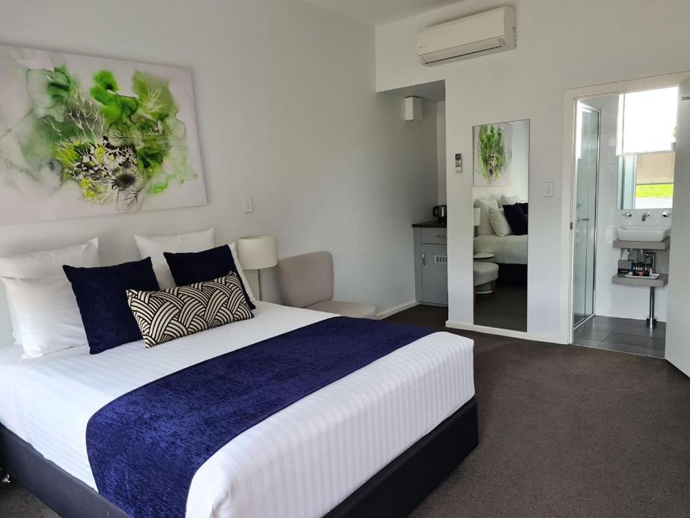 a bedroom with a large bed and a living room at The Avenue Inn in Naracoorte