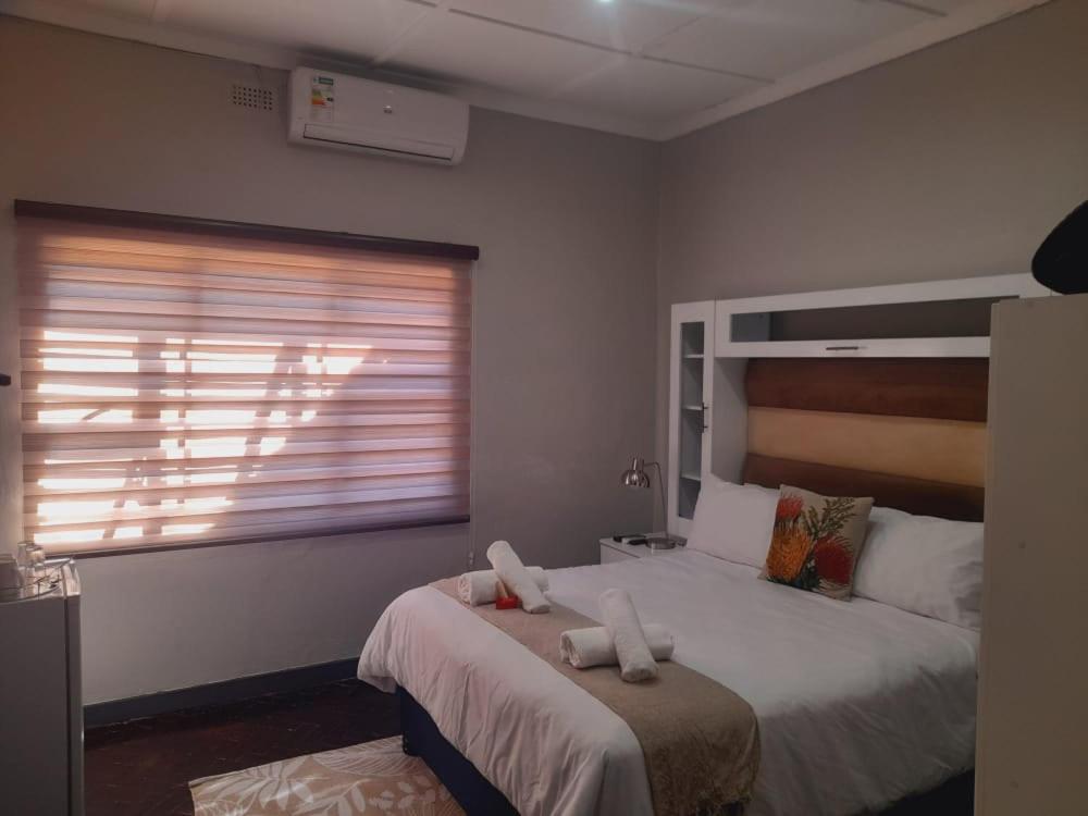 a bedroom with two beds and a window at Palm Guesthouse in Zeerust