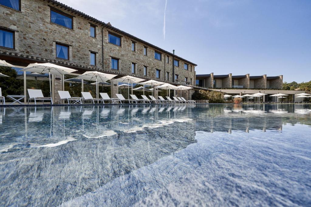 einem Pool mit Stühlen und Sonnenschirmen vor einem Gebäude in der Unterkunft Borgo Lanciano in Castelraimondo