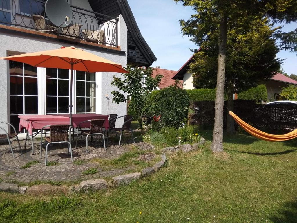 a patio with a table and an umbrella and a hammock at ZACISZNY DOMEK Z OGRODEM NAD MORZEM in Rowy