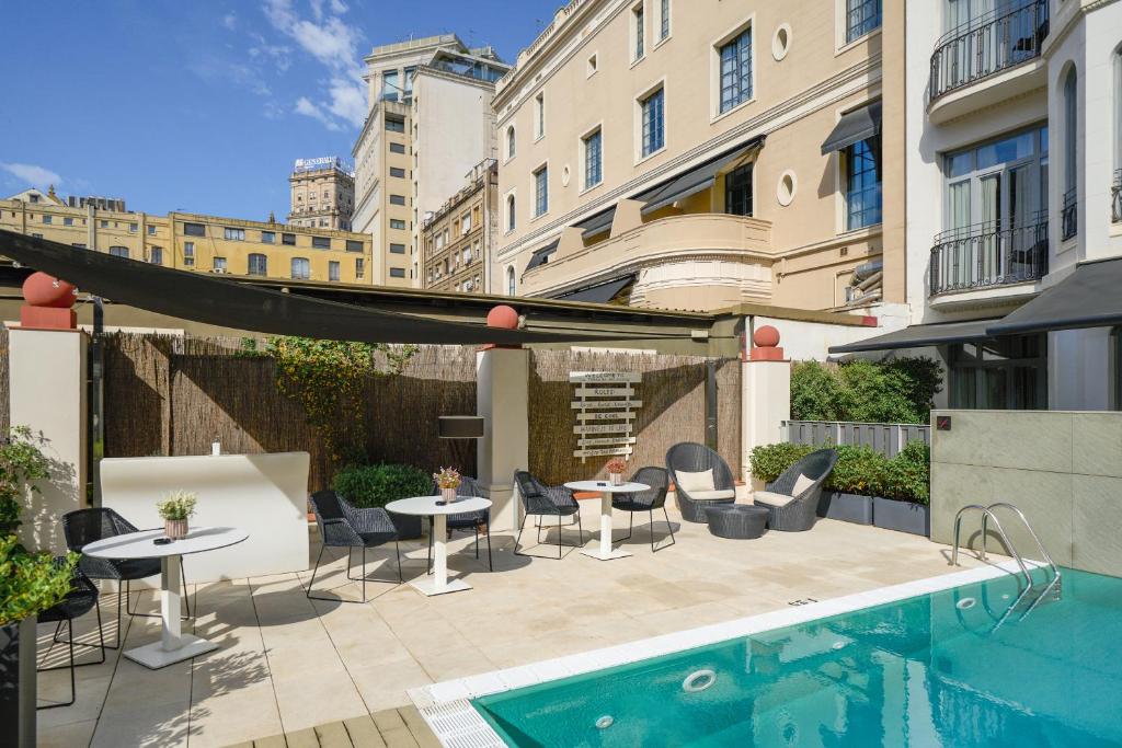 d'une terrasse avec des tables et des chaises à côté de la piscine. dans l'établissement Catalonia Passeig de Gràcia 4* Sup, à Barcelone