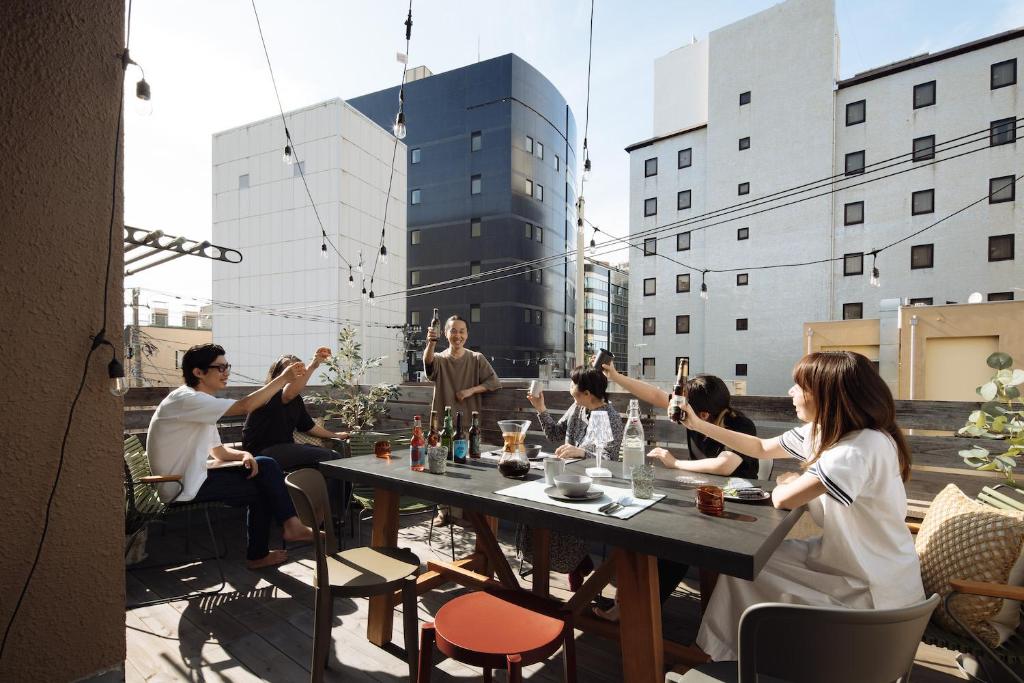 un grupo de personas sentadas en una mesa en una azotea en Good Neighbors, en Kanazawa