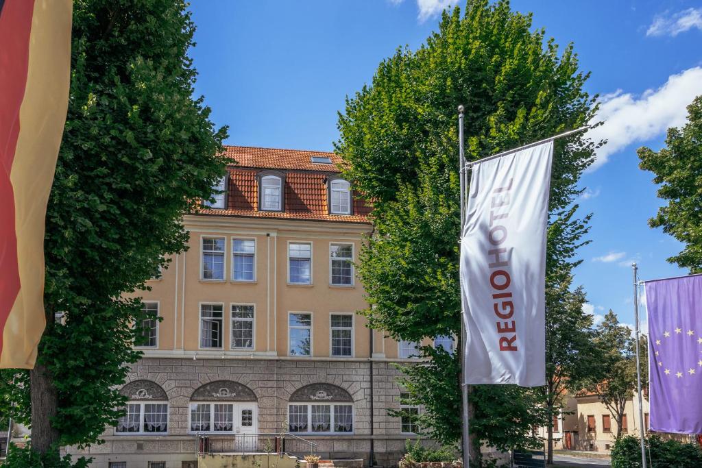 un edificio con una bandera delante de él en REGIOHOTEL Quedlinburger Hof Quedlinburg en Quedlinburg