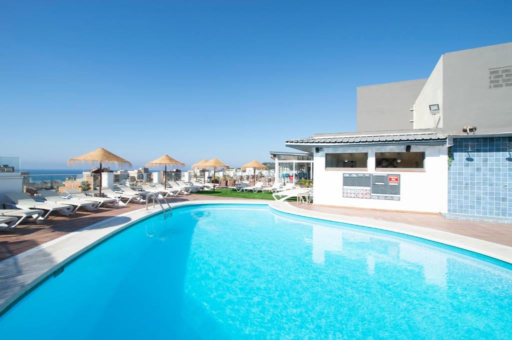 a swimming pool with chairs and the ocean in the background at Hotel Lloret Santa Rosa by Pierre & Vacances in Lloret de Mar