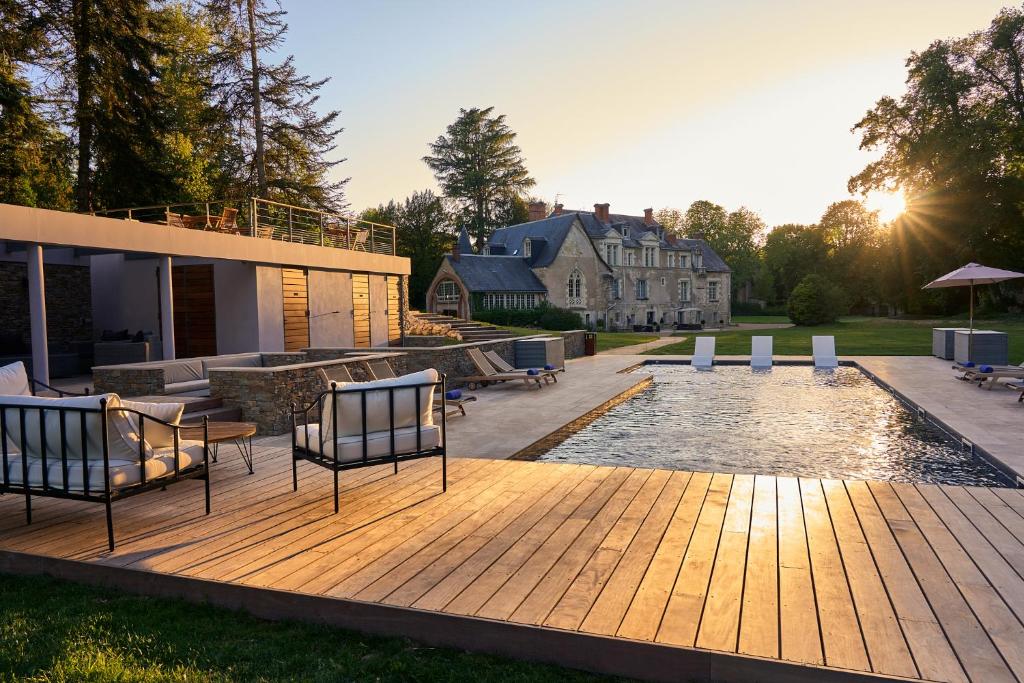 a deck with chairs and a pool in front of a house at Domaine de la Commanderie de Ballan in Ballan-Miré