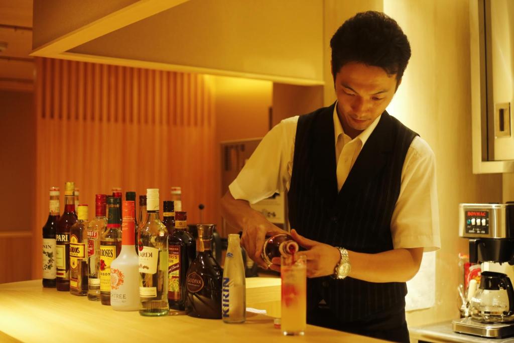 a man standing in a kitchen preparing a drink at Yuraku Kinosaki Spa & Gardens in Toyooka