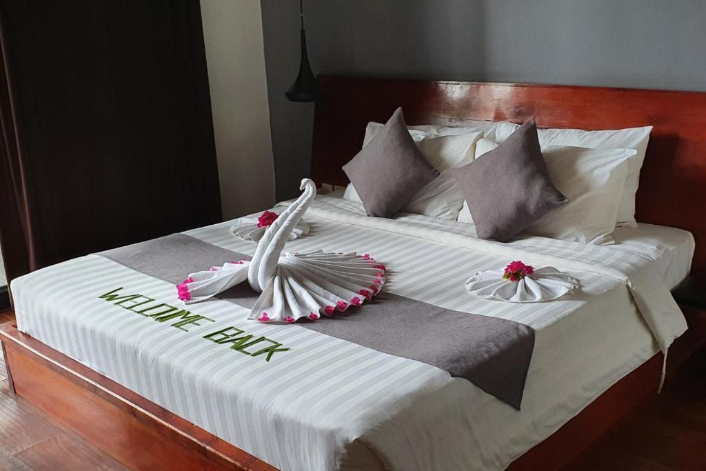 a white bed with two swans on top of it at Siem Reap Tevi Residence in Siem Reap