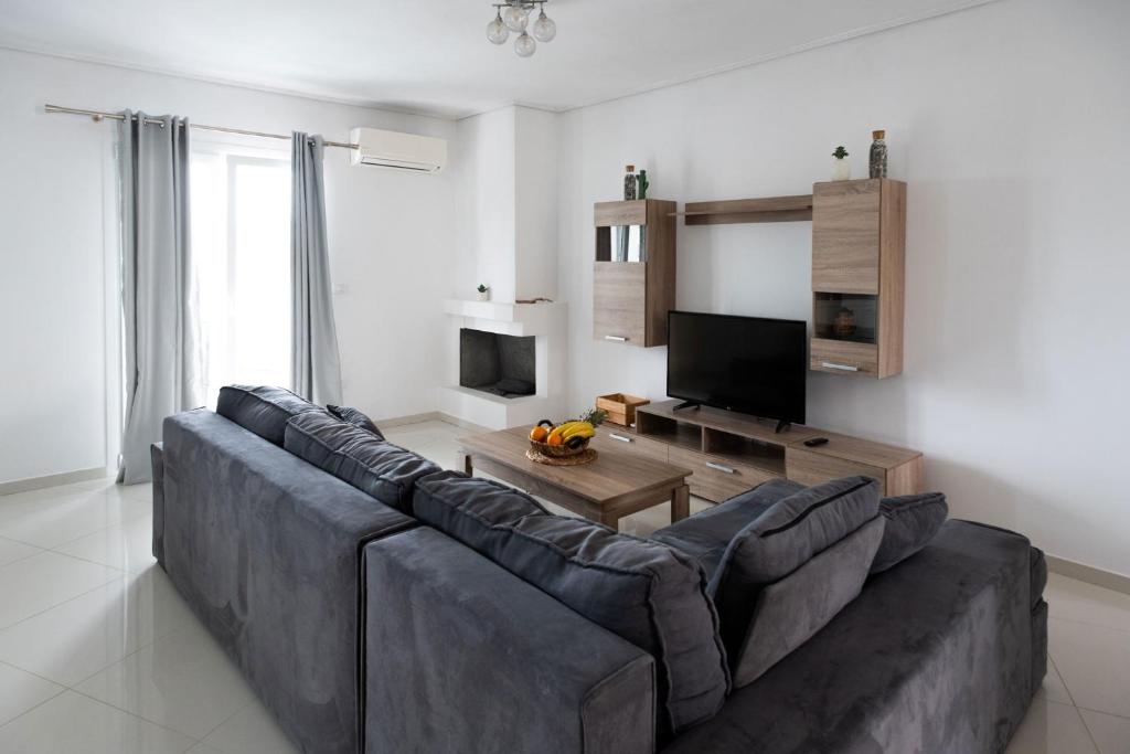 a living room with a large couch and a television at Iridanos Apartments in Skiathos