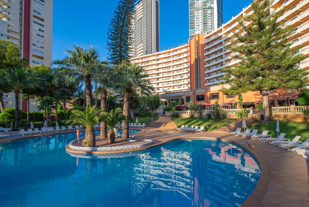 une grande piscine avec des palmiers et des bâtiments dans l'établissement Hotel Benidorm East by Pierre & Vacances, à Benidorm