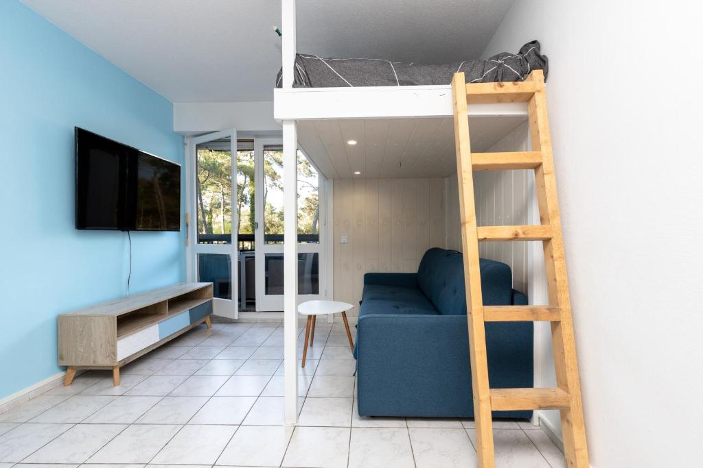 a room with a bunk bed and a couch and a ladder at Studio Seignosse proche plage in Seignosse