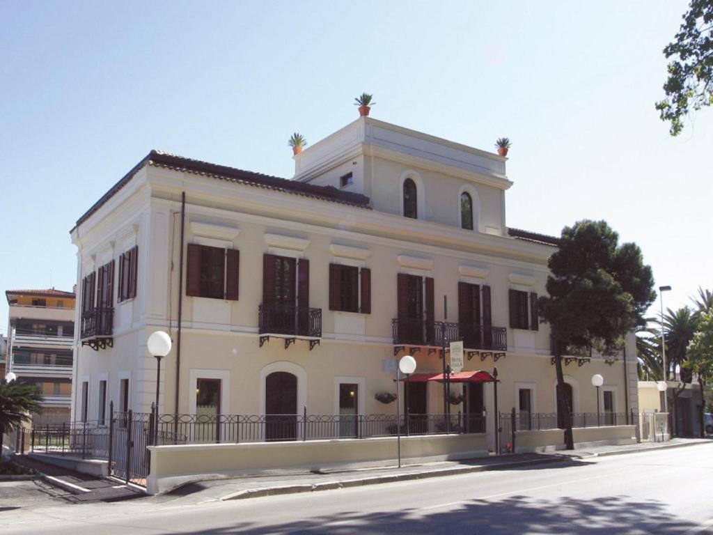 een groot wit gebouw met zwarte luiken op een straat bij Hotel Claila in Francavilla al Mare