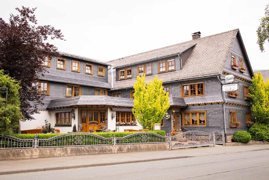 una gran casa gris con una valla delante en Landgasthaus Steffes Hof, en Bad Berleburg