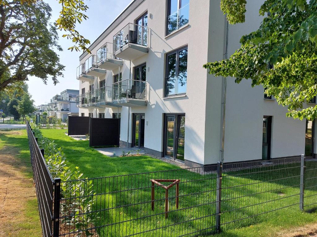 een wit gebouw met een hek ervoor bij Sporthotel Neuruppin - Apartmenthaus mit Ferienwohnungen in Neuruppin