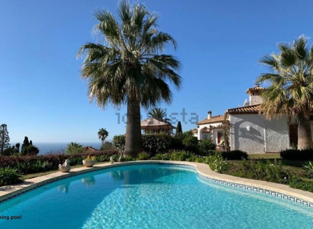 una piscina frente a una casa con palmeras en Villa Tropical Dream, en Salobreña