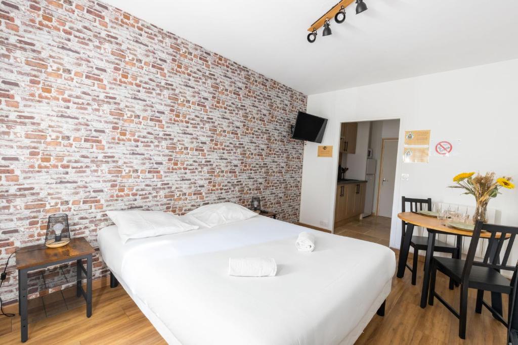 Un dormitorio con una pared de ladrillo y una cama en Studio Elément - Feu, en Saint-Aignan