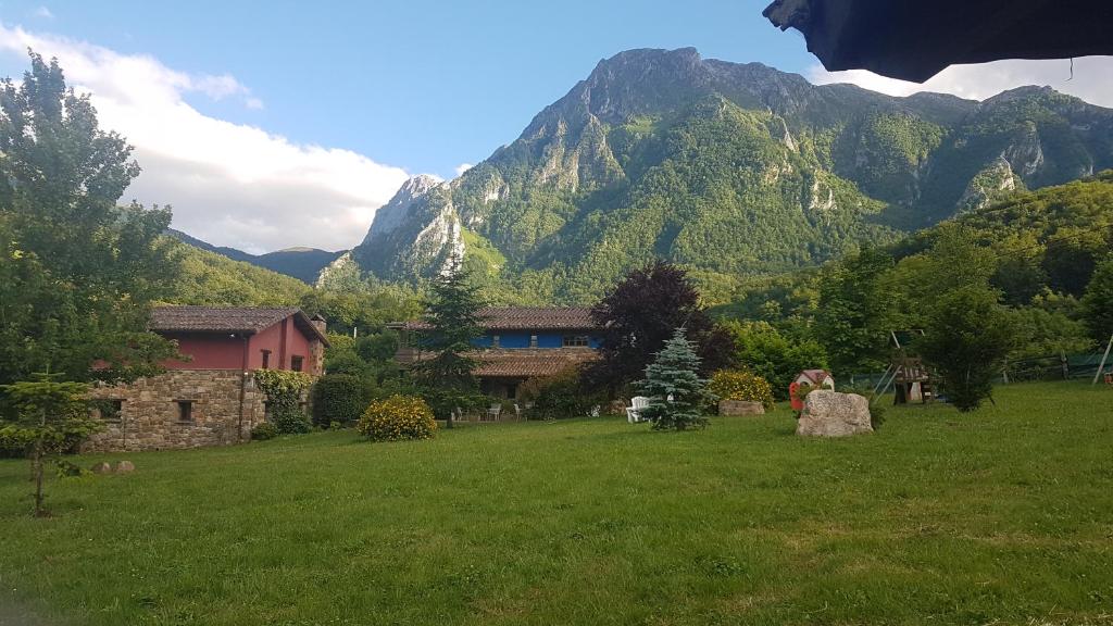 una casa en un campo con montañas en el fondo en Valle de Bueida, casas con jacuzzi en el El Palacio y Viscárcel, en Bárzana