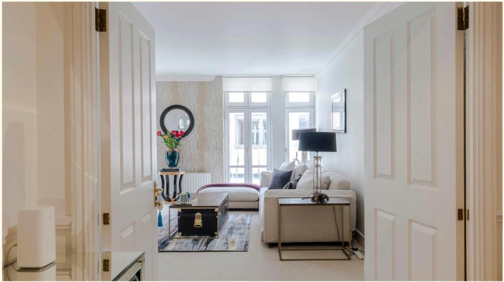 um quarto branco com uma cama e um espelho em Maddox House em Londres