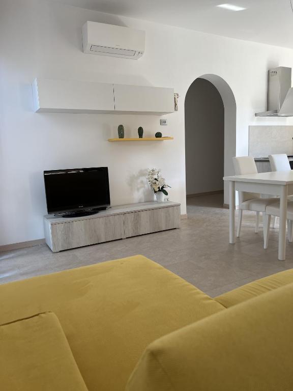 ein Wohnzimmer mit einem Sofa, einem TV und einem Tisch in der Unterkunft Il Timone in Toscolano-Maderno