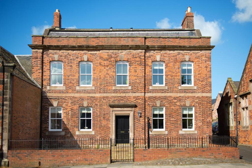 an old red brick building with a blue sky in the background at Parade School Guest Rooms in Berwick-Upon-Tweed