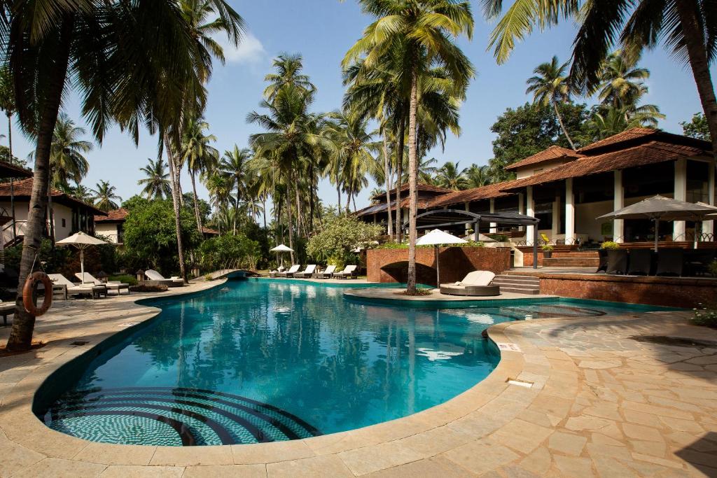 a swimming pool at a resort with palm trees at Coconut Creek Resort - Dabolim Airport in Bogmalo