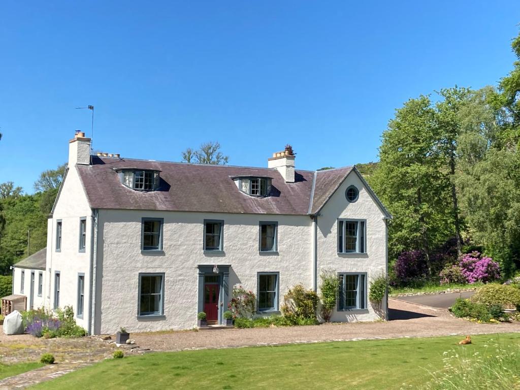 una gran casa blanca con puerta roja en Bedrule Old Manse B&B, en Hawick