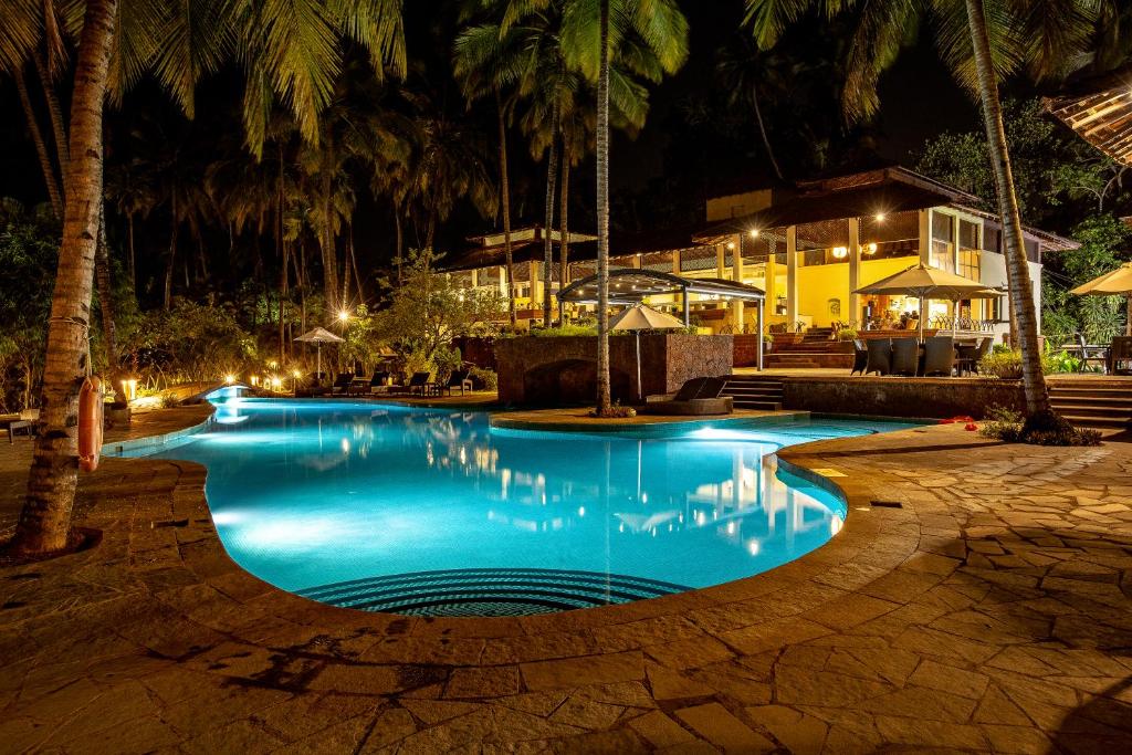 a swimming pool at night with palm trees at Coconut Creek Resort in Bogmalo
