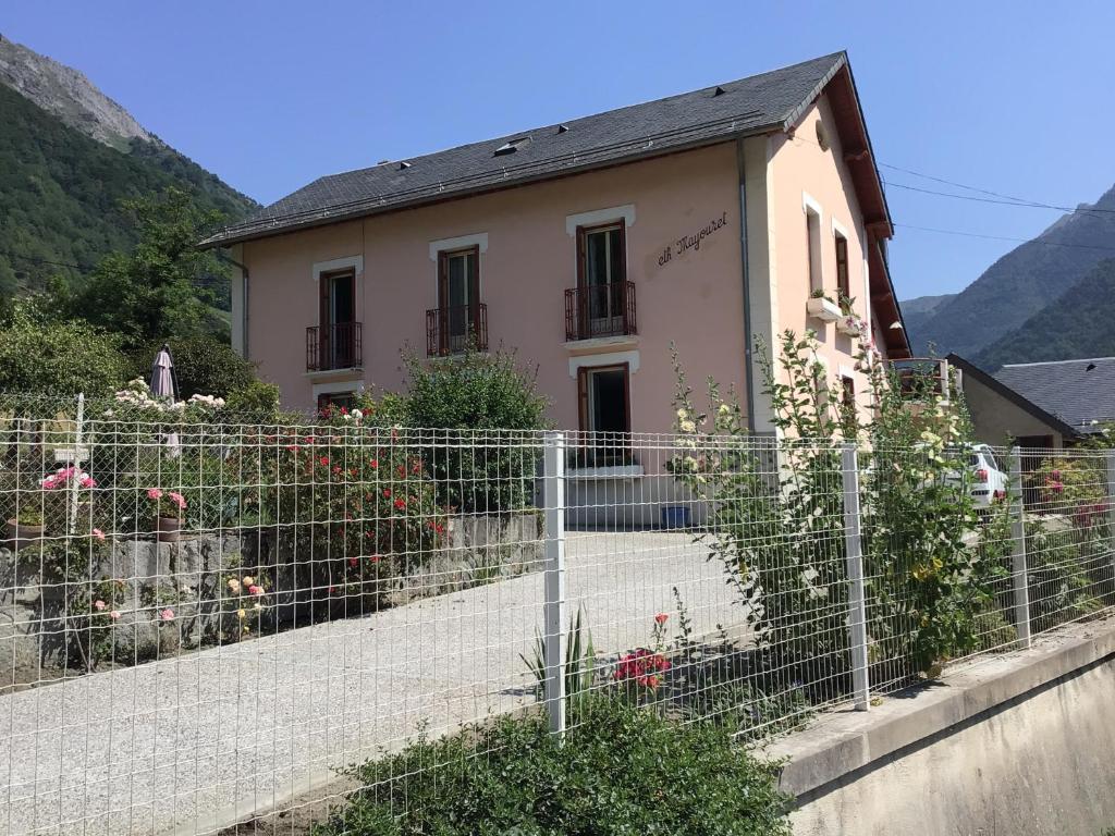 dom za płotem z kwiatami przed nim w obiekcie Villa Eth Mayouret w mieście Cauterets