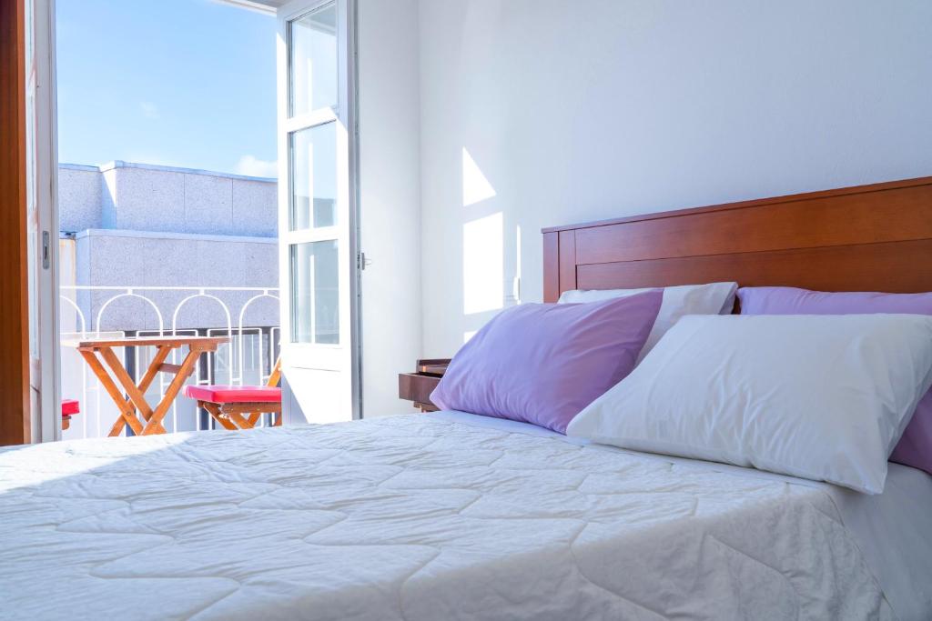 a bedroom with a white bed with a large window at Hotel Terra Linda in Viana do Castelo