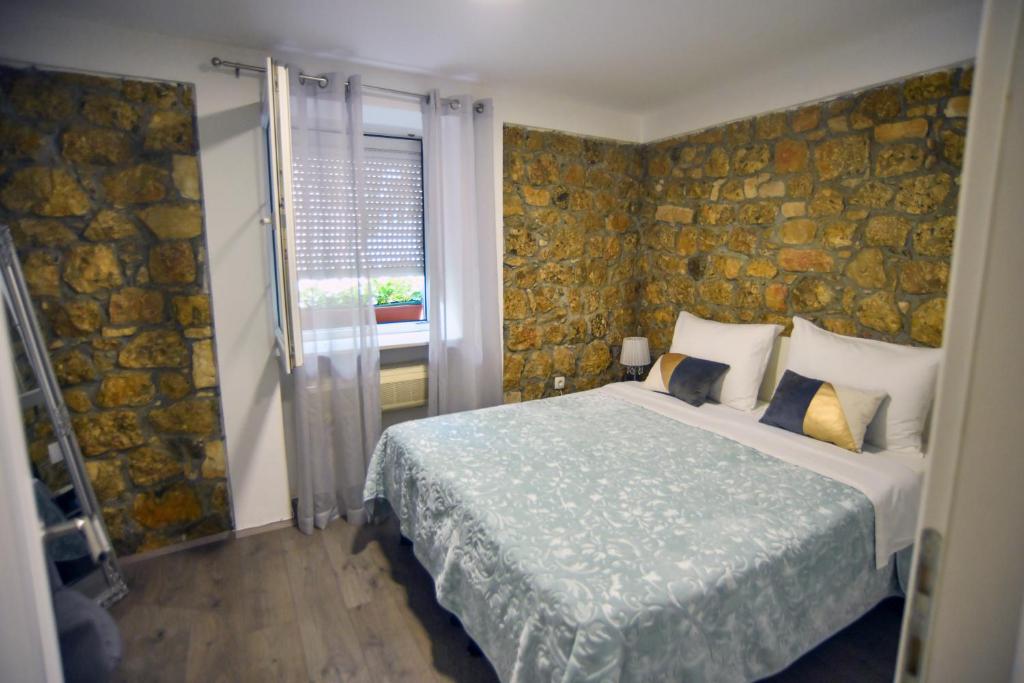 a bedroom with a bed and a stone wall at Luxury apartments Petrovac in Sinj