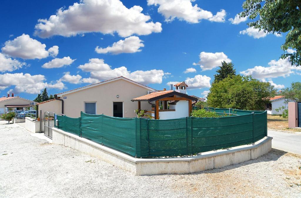 a green fence in front of a house at House Peroj 2195 in Peroj