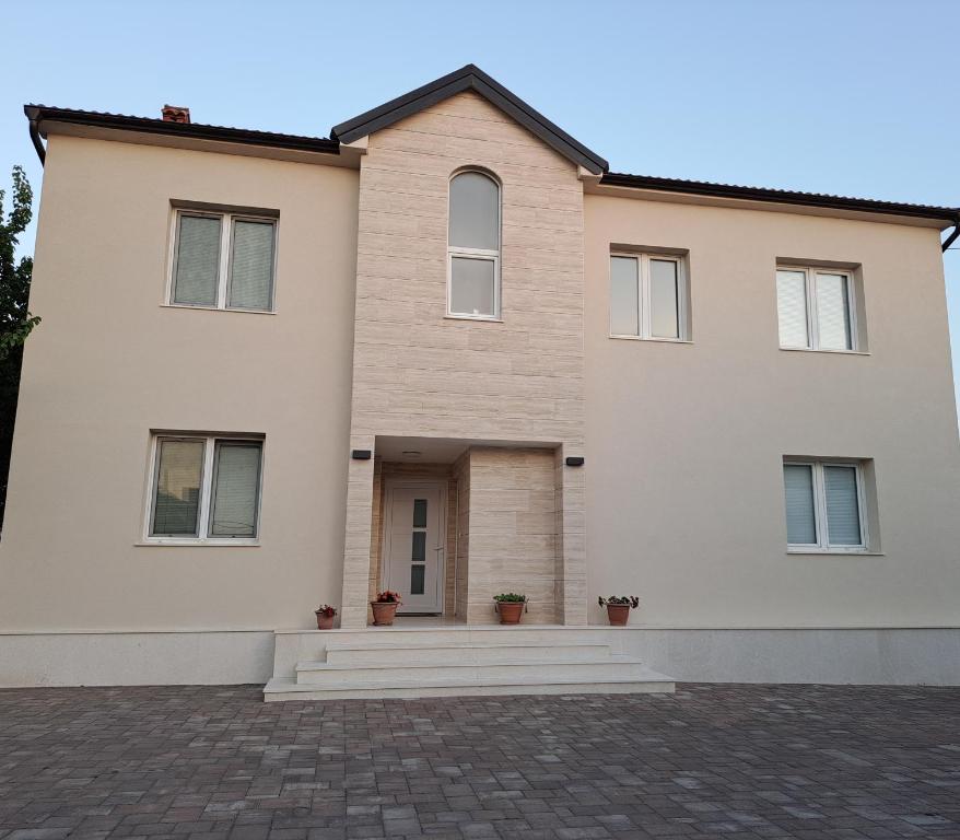 ein großes weißes Haus mit einer Ziegelsteinfahrt in der Unterkunft Guesthouse Emma in Zadar