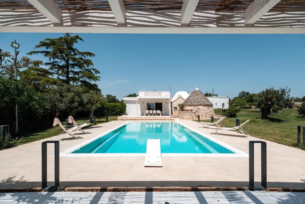 - une piscine avec des chaises et une maison dans l'établissement HelloAPULIA - Design Trulli Sampaolo with private pool, à Gioia del Colle