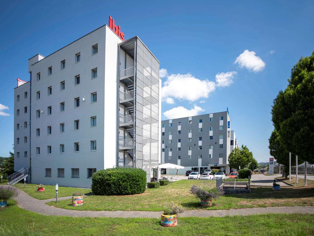 a white building with a red hotel sign on it at ibis Fribourg in Fribourg